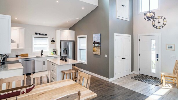 A modern kitchen with white cabinets, a central island, and a 'Welcome' sign.