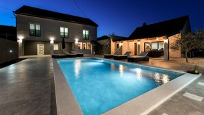 A swimming pool with lounge chairs and a house in the background. - Luxurious home in Prkos (Prkos)