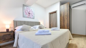 A neatly made bed with pillows and folded towels, a bedside table with a lamp, and a large painting of a flower on the wall. - Luxurious home in Prkos (Prkos)
