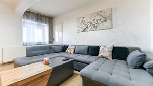 A modern living room with a grey sectional sofa, a wooden coffee table, and a floral painting on the wall. - Luxurious home in Prkos (Prkos)