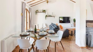 A dining area with a glass table, white chairs, and a TV in the background. - La Manga Club Los Altos Townhouse 489 (Atamaría)