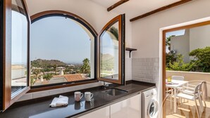 A kitchen with a large window, a washing machine, and a view of a hillside. - La Manga Club Los Altos Townhouse 489 (Atamaría)