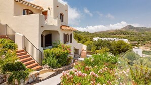 A Mediterranean-style building with a white facade, terracotta roof tiles, and a stone staircase leading to a balcony. - La Manga Club Los Altos Townhouse 489 (Atamaría)