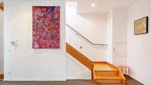 A staircase with a wooden handrail and a red accent wall.