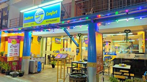 A restaurant with outdoor seating, a sign for 'Southern Comfort Restaurant', and a 'Café' sign advertising fresh coffee and tasty cakes. - Southern Comfort Patong (Patong)