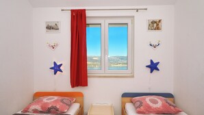 A bedroom with two beds, a window with a red curtain, and star decorations on the wall. - Dani, Home-like sea View Apt, Close to Beach (Trogir)