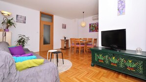 A living room with a sofa, a TV, a dining table with chairs, and a green cabinet with plant designs. - Dani, Home-like sea View Apt, Close to Beach (Trogir)