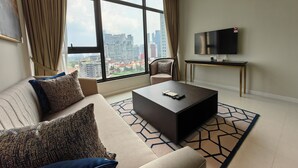 Een moderne woonkamer met een groot raam, een flatscreen televisie, een salontafel en een bank.
