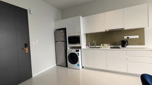 Een moderne keuken met witte kastjes, een ingebouwde magnetron, een wasmachine en een koffiezetapparaat.
