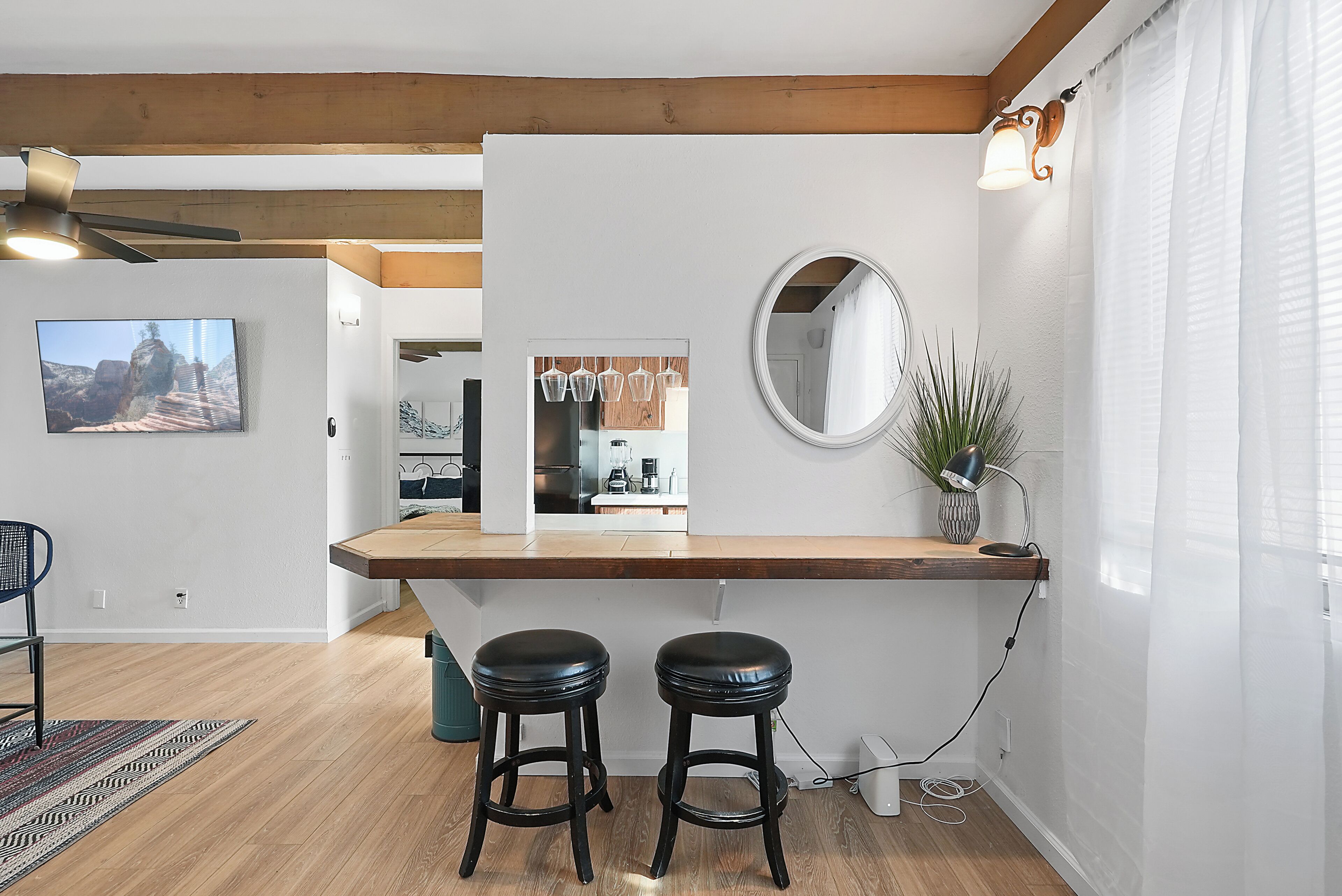 A modern kitchen with wooden countertops, a built-in oven, and a dining area with two stools.
