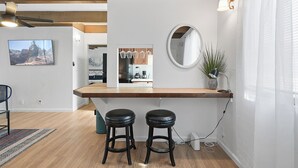 A modern kitchen with wooden countertops, a built-in oven, and a dining area with two stools. - Mission Bay Condo - Steps to Sand, Dining, AC, Parking, Location & Shops! (San Diego)