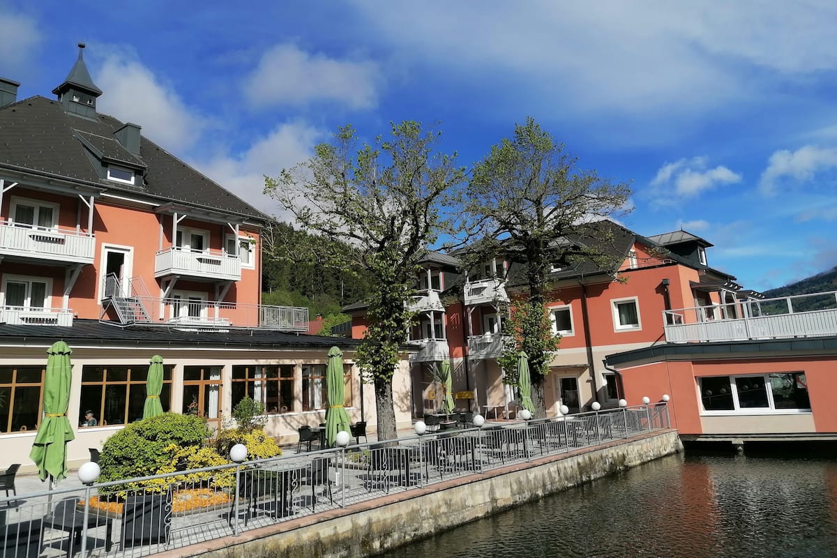 A riverside hotel with balconies, outdoor seating, and a canal.