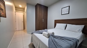 A bedroom with a bed, a wardrobe, and a door. - Lindo AP Praia do Forte - Porto Azul 107 (Cabo Frio)