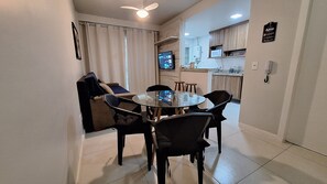 A dining area with a round table and chairs, a ceiling fan, and a kitchen in the background.