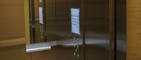 An elevator interior with stainless steel doors, a sign advising to respect the weight limit, and a floor indicator.