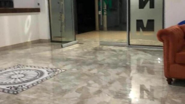 A spacious room with a marble floor, a patterned rug, and a sliding glass door with a frosted glass panel. - YNM Adam's Hotel (Pallisa)
