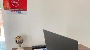 A reception desk with a laptop, a payment terminal, and a sign indicating card acceptance. - YNM Adam's Hotel (Pallisa)