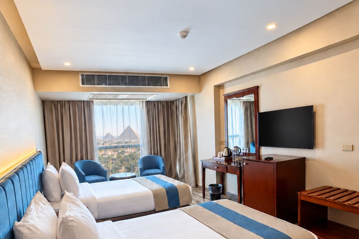 Une chambre d’hôtel avec deux lits, un bureau, une télévision et une vue sur le paysage urbain.