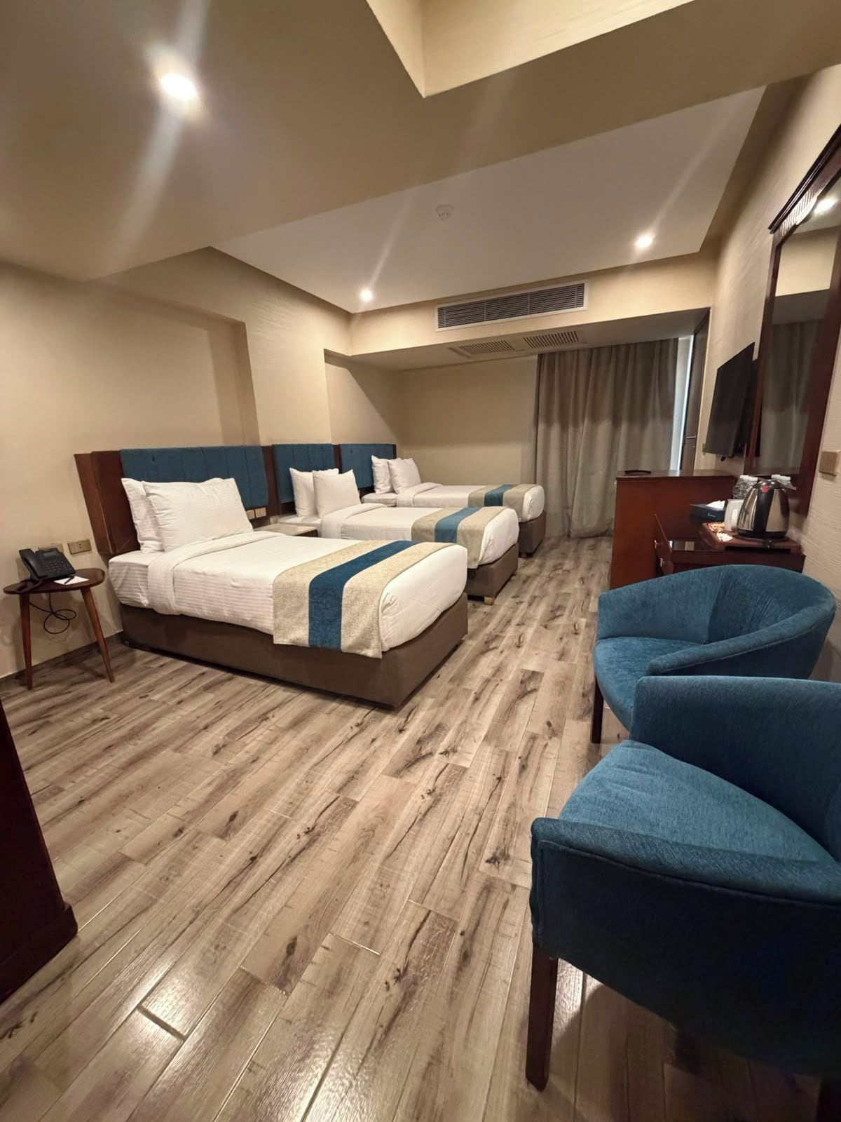 A hotel room with two beds, a desk, a chair, and a television.