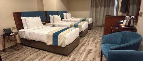 A hotel room with two beds, a desk, a chair, and a television.