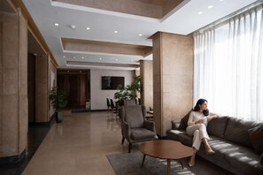 A modern lobby with a sofa, chairs, a coffee table, and a dining area in the background. - Stay Inn Pyramids Hotel (Giza)