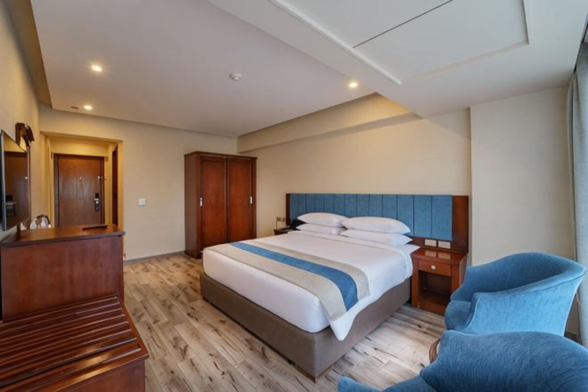 A hotel room with a bed, a desk, a chair, and a wardrobe.
