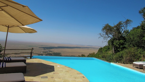 A swimming pool with a view of the countryside, surrounded by lounge chairs and an umbrella. - Ahadi Mara Camp (Maasai Mara)