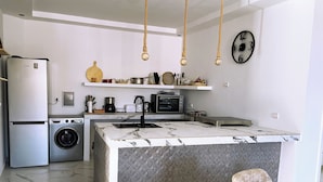 A modern kitchen with a central island, built-in appliances, and a hanging light fixture. - Entire house with private roof terrace (Al Hoceima)