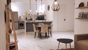 A modern living room with a marble floor, a round dining table with chairs, a sofa, and a small side table. - Entire house with private roof terrace (Al Hoceima)