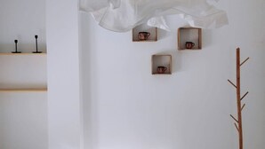 A minimalist bedroom with a bed, a coat rack, and three small wooden shelves with cups. - Entire house with private roof terrace (Al Hoceima)