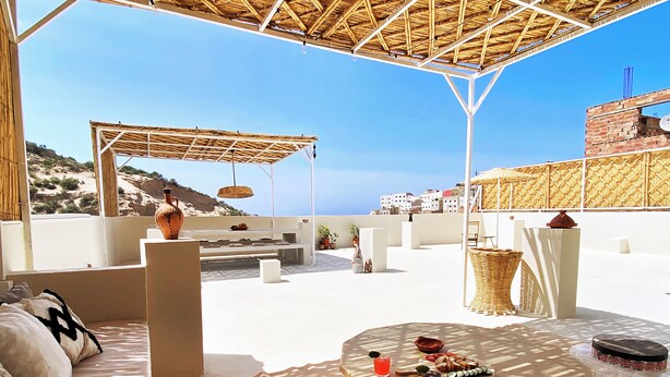 An outdoor seating area with a table, cushions, and a view of the sea. - Entire house with private roof terrace (Al Hoceima)