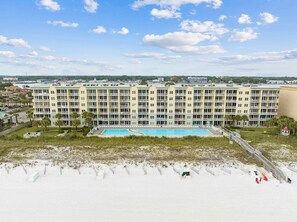 A multi-story hotel with a swimming pool, located near a beach.