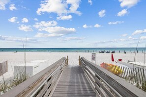 A wooden boardwalk leading to a beach with clear skies and calm waters.