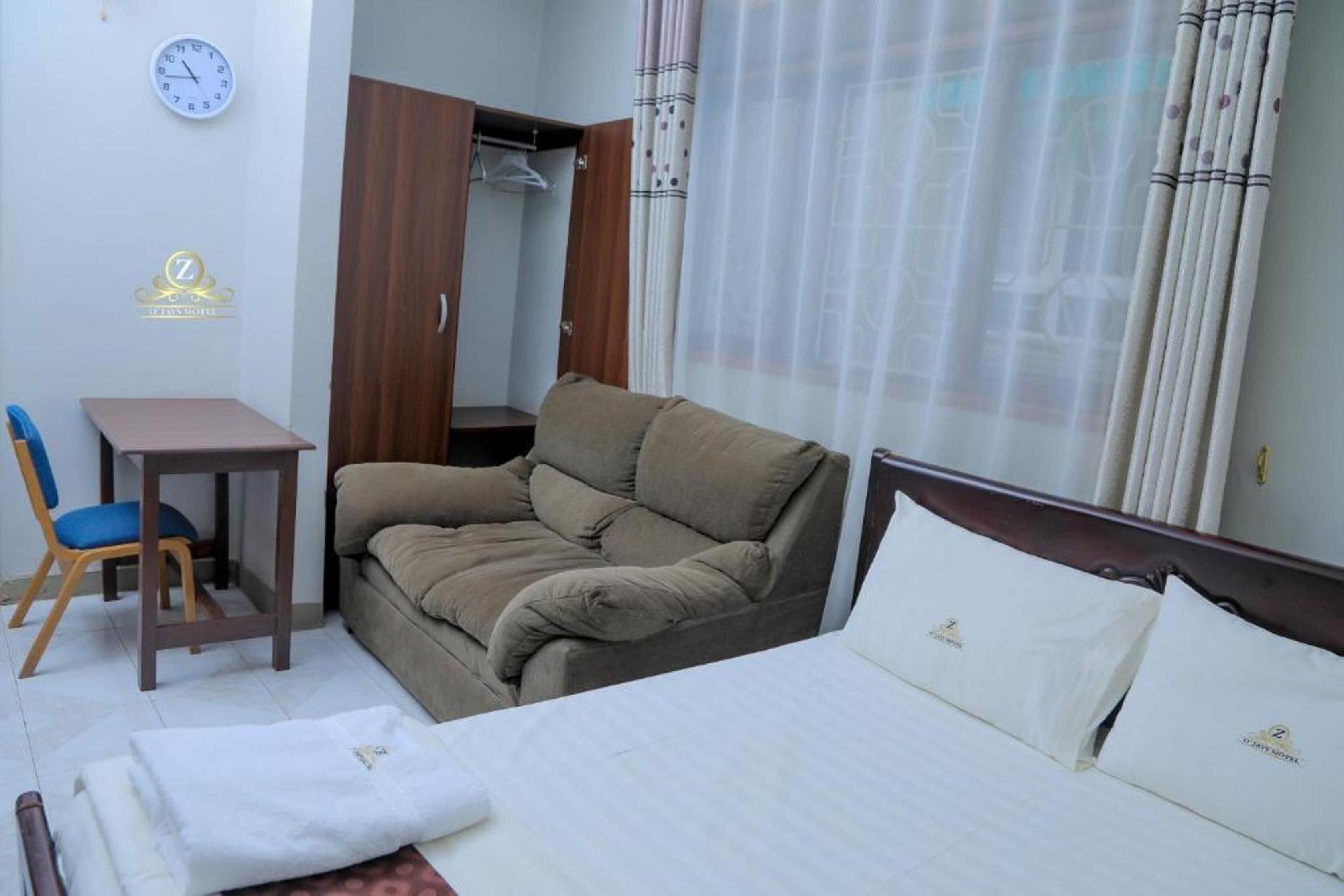 A hotel room with a bed, a sofa, a desk, and a wardrobe.