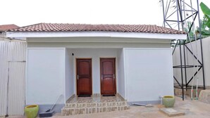 A building with a tiled roof, two wooden doors, and a small set of steps leading to the entrance.