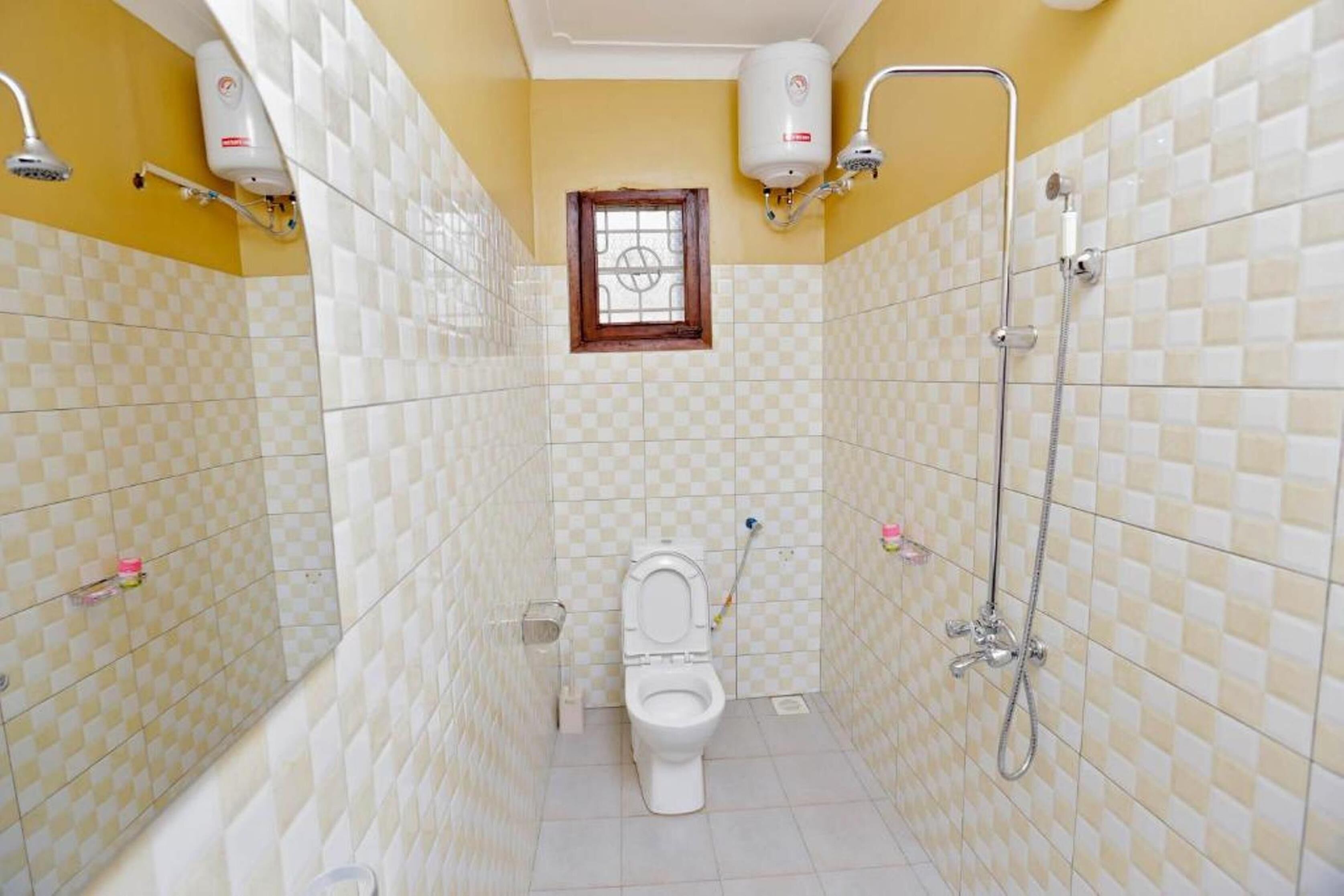 A bathroom with a toilet, a shower, and two wall-mounted water heaters.