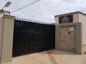 A gated entrance to O'Jays Motel with a sign indicating it offers bed and breakfast services. - O'Jays Motel (Kampala)