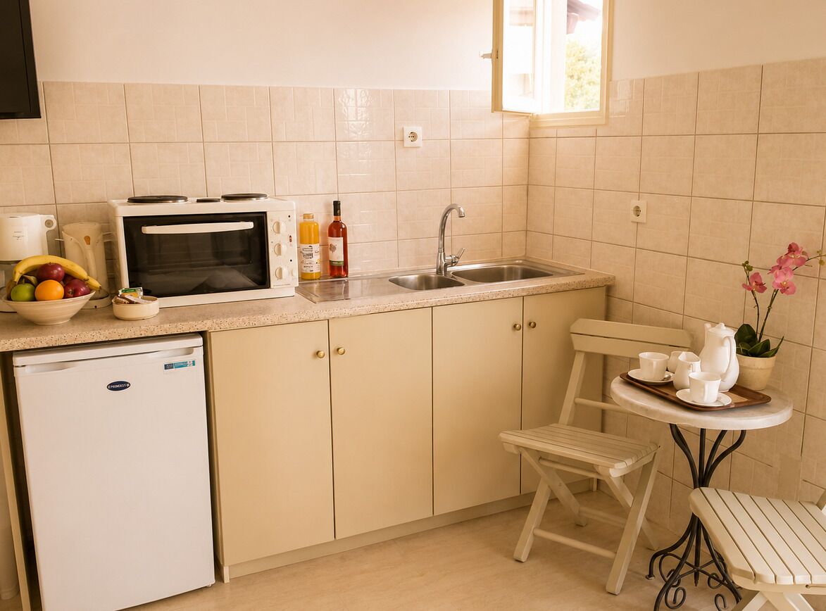 A compact kitchen with a microwave, sink, and a small refrigerator. There is a dining area with a table and chairs.