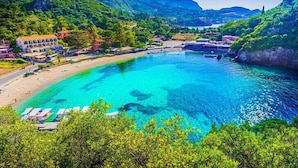 A coastal resort with clear turquoise waters, a sandy beach, and lush greenery. - Pierhouse Hotel Corfu - Gouvia (Gouvia)