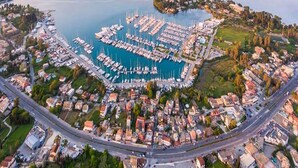 An aerial view of a marina with numerous boats docked, surrounded by residential buildings and a road. - Pierhouse Hotel Corfu - Gouvia (Gouvia)