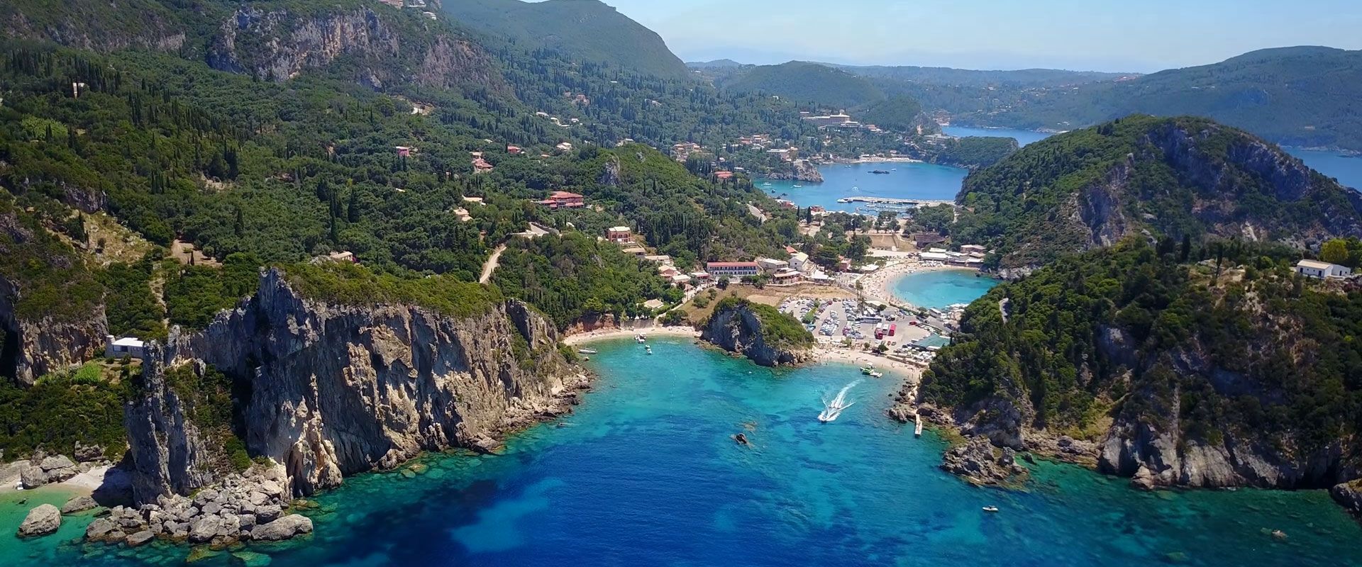 A coastal area with rocky cliffs, clear blue waters, and a small beach.