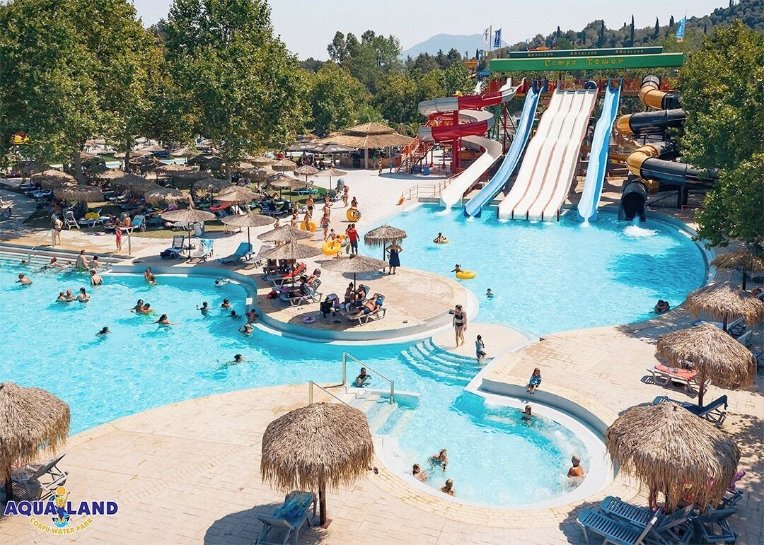 A water park with multiple pools, slides, and thatched umbrellas.