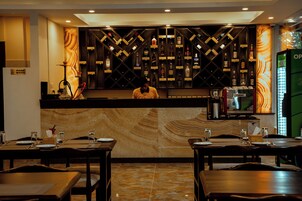 Un restaurante con zona de bar, mostrador y mesas dispuestas para comer.