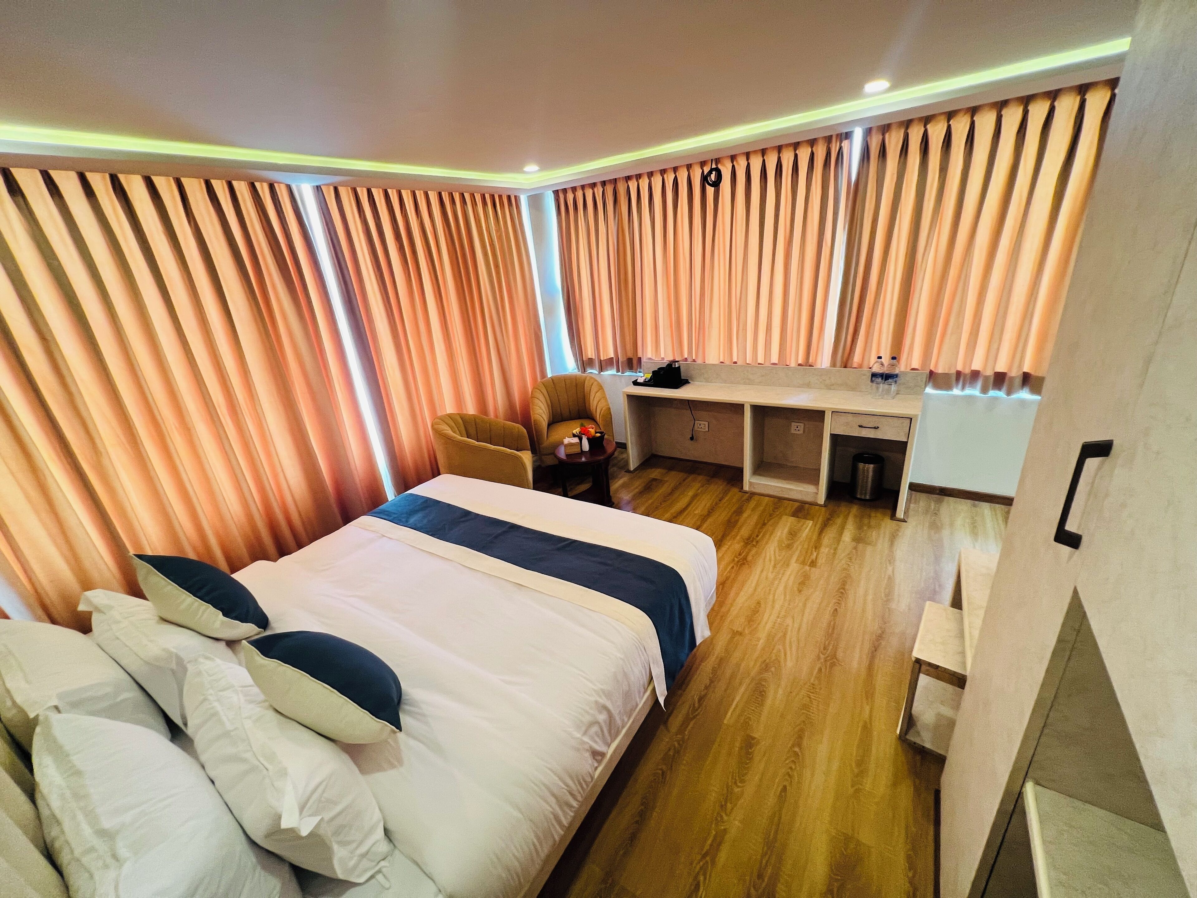 A hotel room with a large bed, a desk, and a chair.