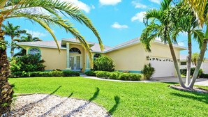 A single-story house with a well-maintained lawn, a driveway, and a garage. - Cape Coral Waterfront Vacation Rental with Heated Pool and Boat Dock. (Cape Coral)
