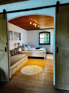 Un dormitorio acogedor con cama, sofá, ventana y techo de madera.