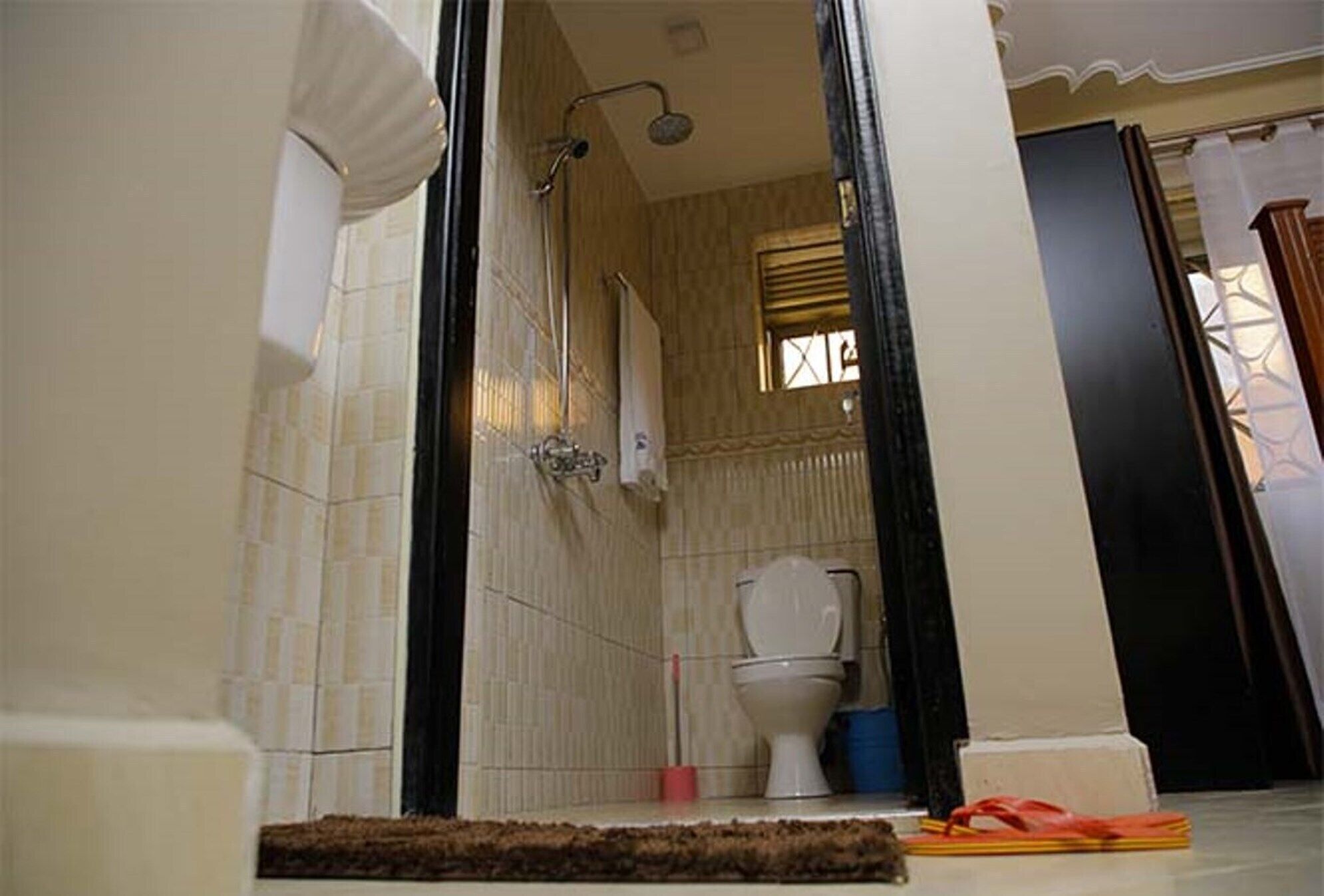A bathroom with a shower, toilet, and a visible window.
