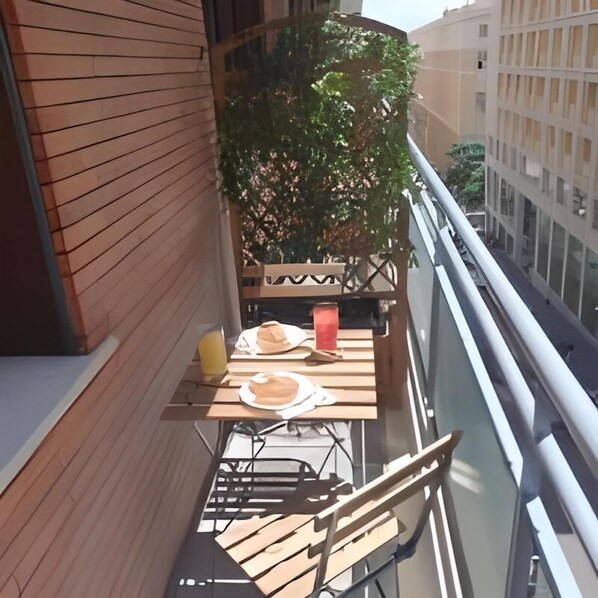 A balcony with a wooden table set for two, a chair, and a potted plant. - Le Sciantose Relais (Naples)