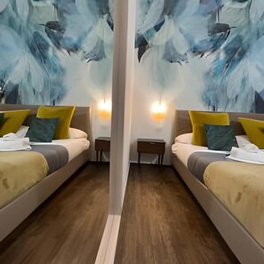 A hotel room with two beds, each with a pillow and a bedside table. - Le Sciantose Relais (Naples)