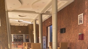 A spacious lobby with a high ceiling, large columns, and a seating area with chairs. - Country Motel (Rubaare)